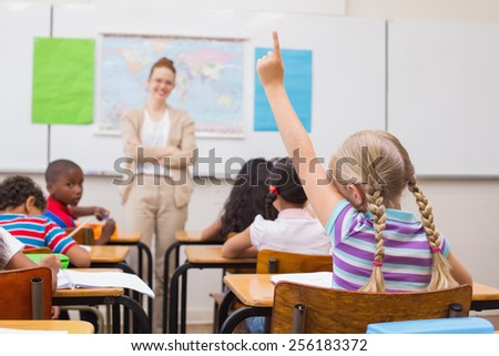 Pupil raising hand during geography lesson in classroom at the elementary school