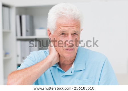 Portrait of senior male patient suffering from neck ache in clinic