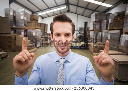 Smiling warehouse manager pointing up with finger in a large warehouse