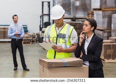 Warehouse manager and worker talking in a large warehouse