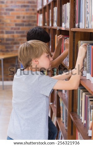 Cute pupils looking for books in library at the elementary school