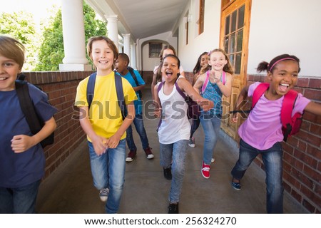 Cute pupils running down the hall at the elementary school