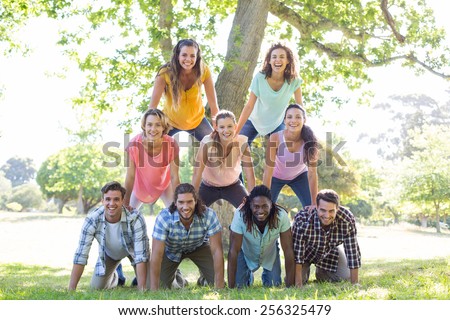 Happy friends in the park making human pyramid on a sunny day