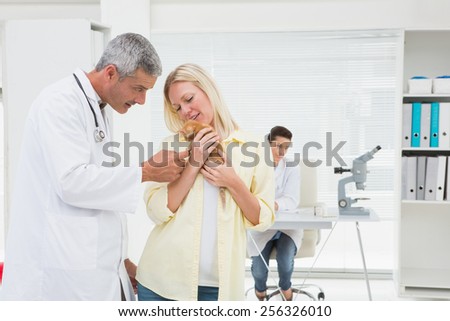 Veterinarian looking cat in it owner arms in medical office