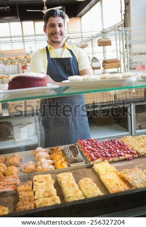 Smiling server standing with arms crossed behind the counter at the bakery