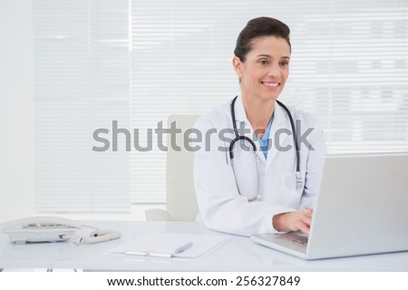 Smiling doctor using laptop in medical office
