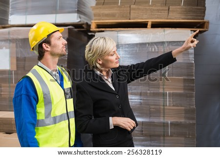 Warehouse manager pointing something to his colleagues in a large warehouse