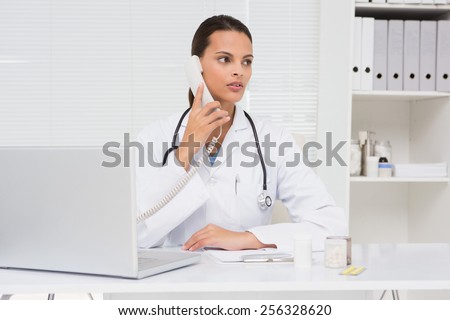 Vet phoning and using laptop in medical office