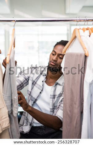 Portrait of male fashion designer looking at rack of clothes