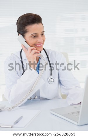 Veterinarian phoning and using laptop in medical office