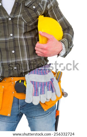 Manual worker wearing tool belt while holding helmet on white background