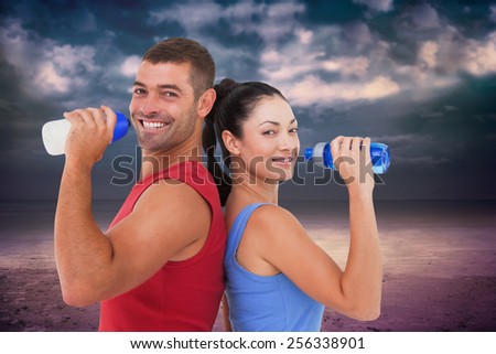 Fit man and woman smiling at camera together against dark cloudy sky