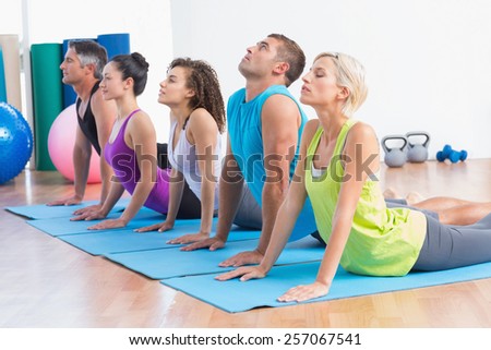 Men and women doing yoga stretch in gym class