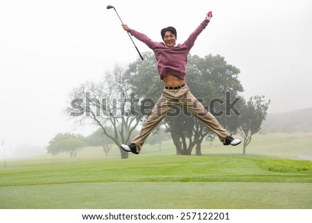 Excited golfer jumping up and smiling at camera at the golf course