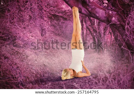 Fit young woman doing the shoulder stand pose against path in autumnal forest