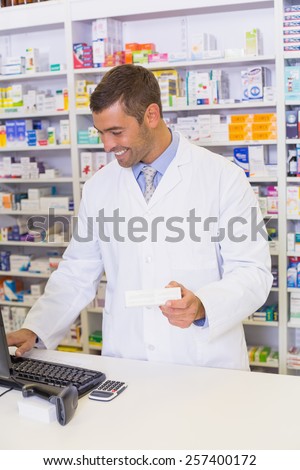 Handsome pharmacist holding medicine box at the hospital pharmacy