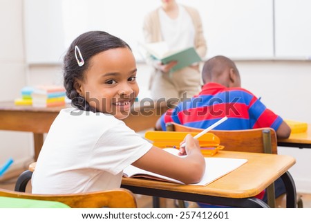 Cute pupil smiling at camera in classroom at the elementary school