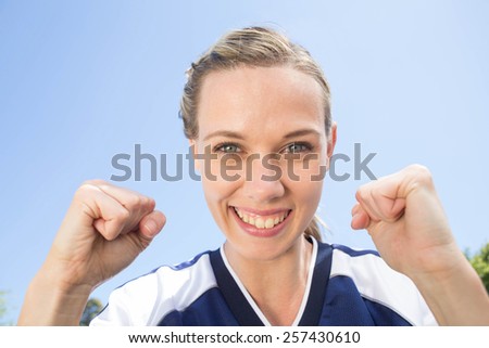 Pretty football player smiling at camera on a sunny day