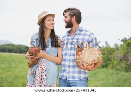 Happy farmers holding chicken and eggs on a sunny day