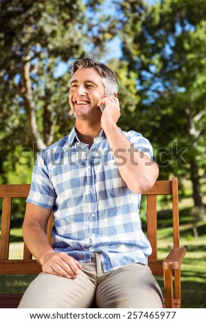 Man sitting on park bench with phone on a sunny day