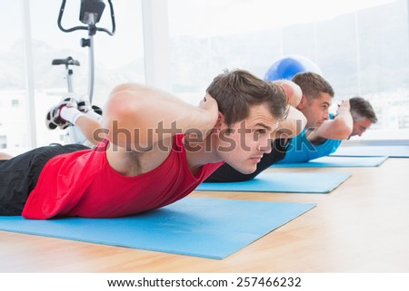 Group of men working on exercise mat in fitness studio