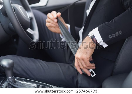 Businessman putting on his seat belt in his car