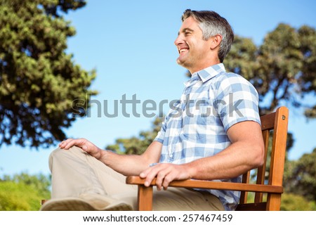Casual man relaxing on park bench on a sunny day