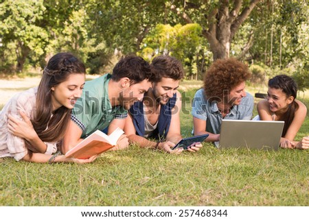 Happy friends in the park studying on a sunny day
