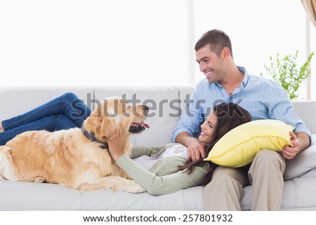 Happy couple with dog on sofa at home