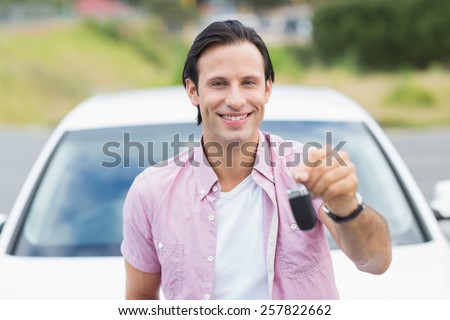 Man smiling and showing key outside his car