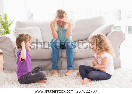 Upset woman sitting on sofa while brother teasing sister at home
