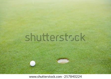 Golf ball next to hole at the golf course