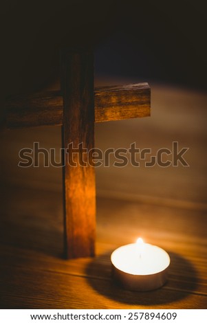Candle and wooden cross on wooden table