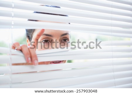 Woman peeking through blinds from outside