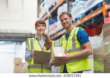 Smiling warehouse manager and delivery man in warehouse