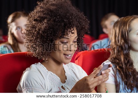 Woman text messaging on her mobile during movie at the cinema