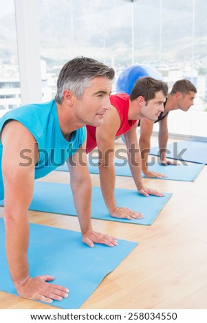 Group of men working on exercise mat in fitness studio