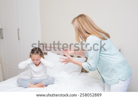 Upset mother scolding her daughter in the bedroom