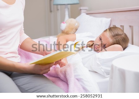 Mother reading daughter a bedtime story at home in the bedroom