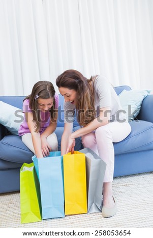 Mother and daughter looking at shopping bags at home in the living room
