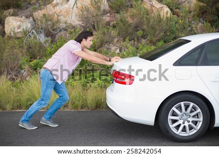 Man pushing car after a car breakdown at the side of the road