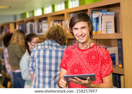 Male college student using digital tablet in the library
