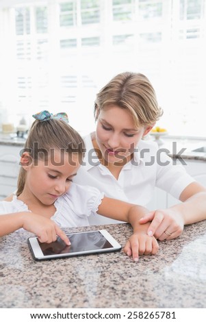 Mother and daughter using tablet pc at home in kitchen