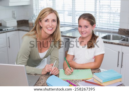 Happy mother helping daughter doing homework