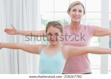 Happy mother and daughter doing yoga at home in the living room