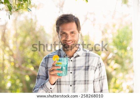 Happy man smiling at camera with drink on a sunny day