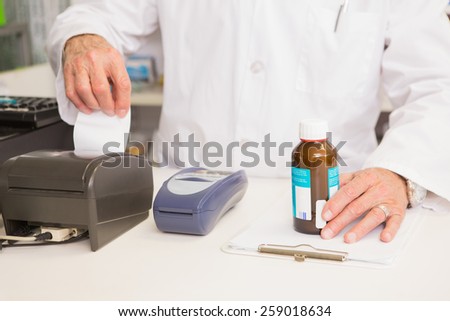 Pharmacist holding jar of medicine and receipt in the pharmacy