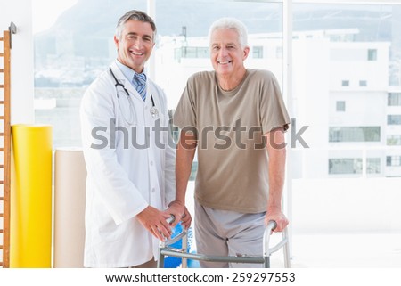 Senior man with therapist smiling at camera in fitness studio