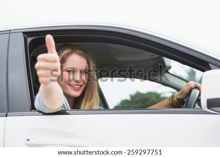 Happy woman sitting in drivers seat thumb up in her car