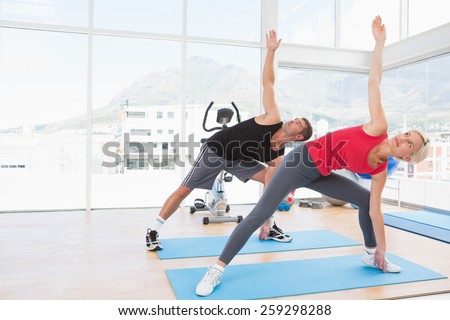 Happy fit couple working on exercise mat in fitness studio